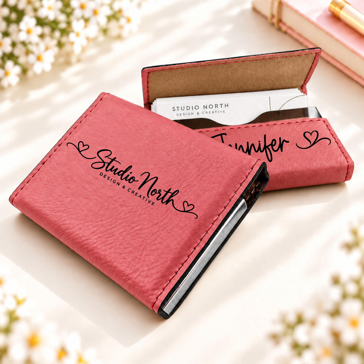 Pink leatherette business card holder engraved with a business name, shown open with cards inside