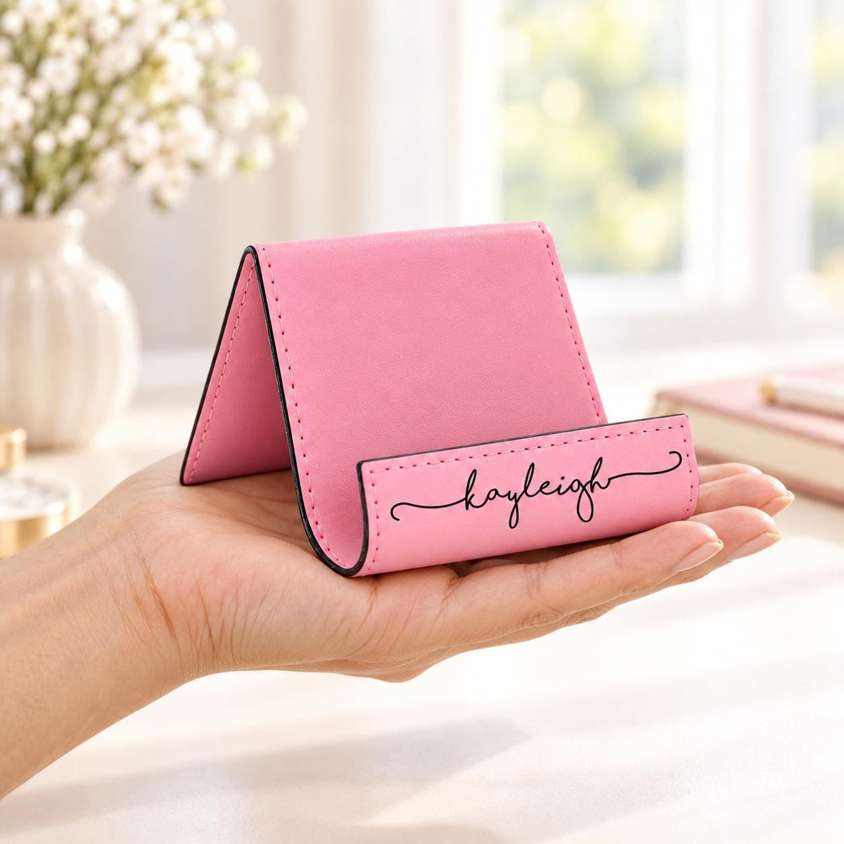 Pink personalized phone stand held in one hand to show its size