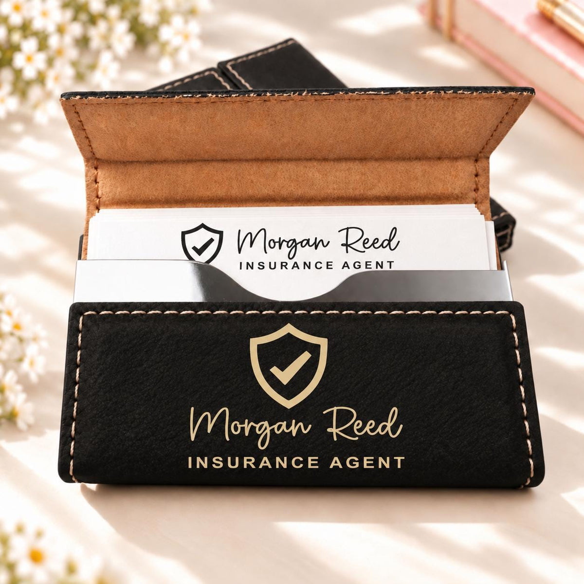 Black and gold business card holder engraved with a shield design, name and title
